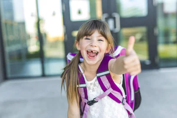 Flicka stående utanför skolan med väska — Stockfoto