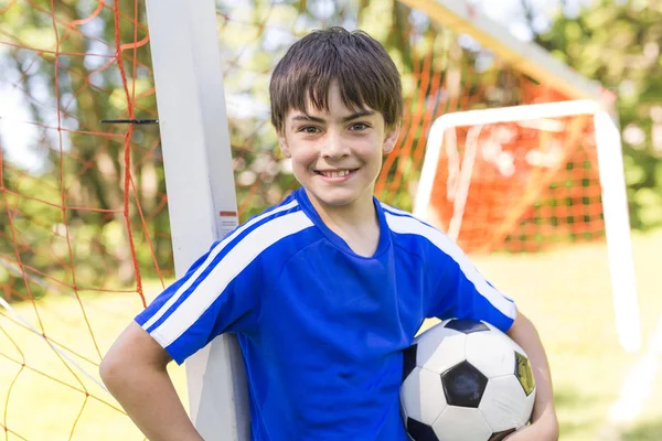 Mladý chlapec s fotbalovým míčem na uniformě sport — Stock fotografie