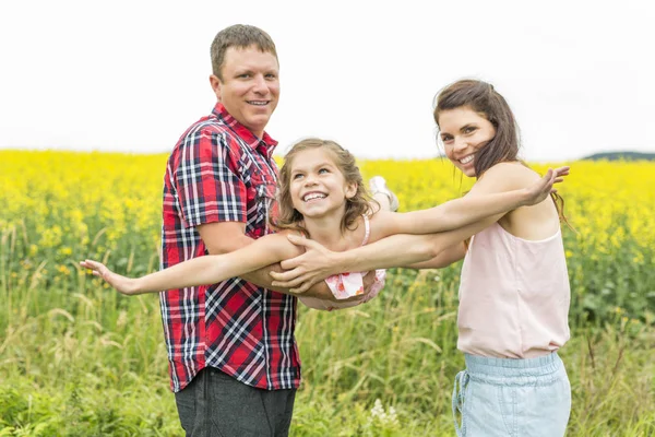 Happy family couple nd child daughter on yellow flowers on nature in summer — Stock Photo, Image