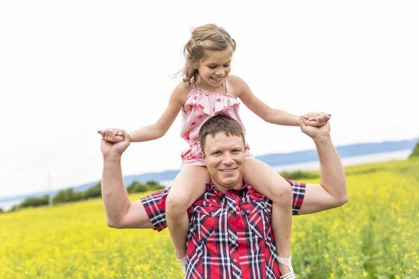 Happy family father and child daughter on yellow flowers on nature in summer — Stock Photo, Image