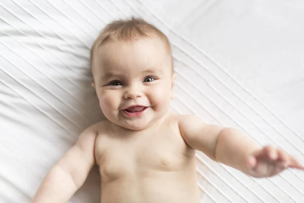 Linda niña feliz de 7 meses en pañal mintiendo y jugando — Foto de Stock