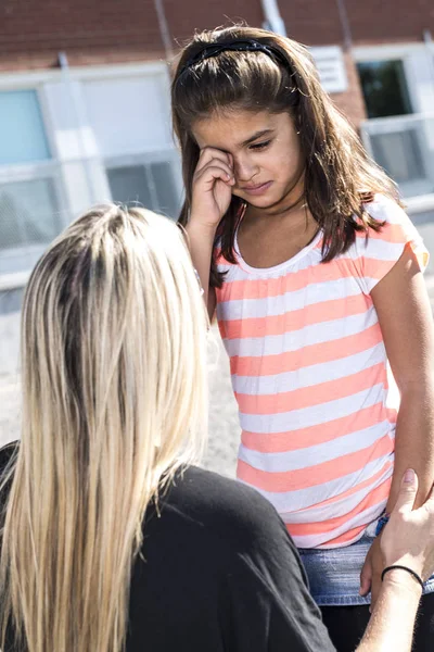 Insegnante consolazione un ragazza su schoolyards — Foto Stock