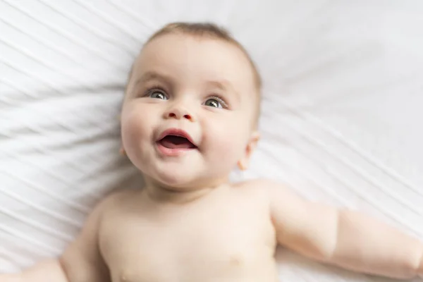 Cute happy 7 month baby girl in diaper lying and playing — Stock Photo, Image