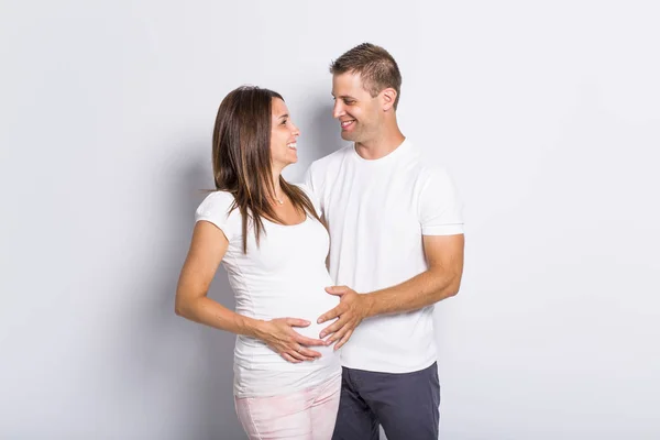 Pareja caucásica esperando bebé sonriendo alegre en blanco — Foto de Stock