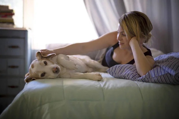 Женщина со своей собакой в постели дома — стоковое фото