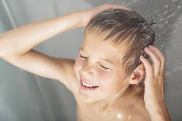 Счастливый мальчик моет голову в душе в ванной комнате — стоковое фото
