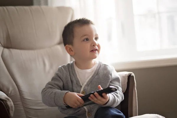 Petit garçon regarde la télé assis sur un canapé — Photo