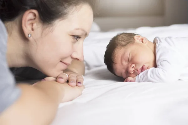 Gelukkig moeder en baby liggend op bed thuis — Stockfoto