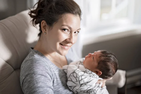 Felice madre che tiene adorabile bambino in salotto — Foto Stock