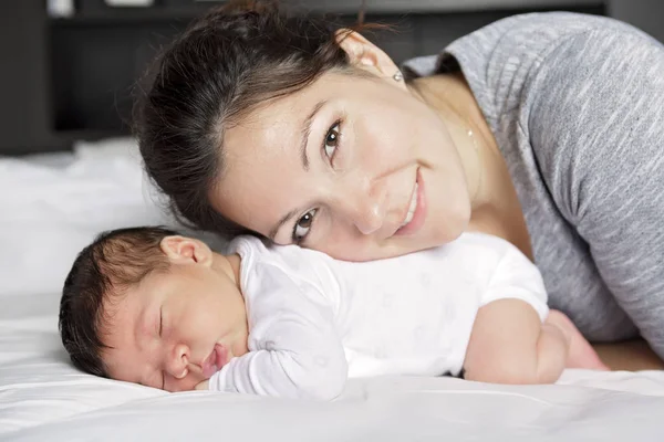 Feliz madre y bebé tumbados en la cama en casa — Foto de Stock