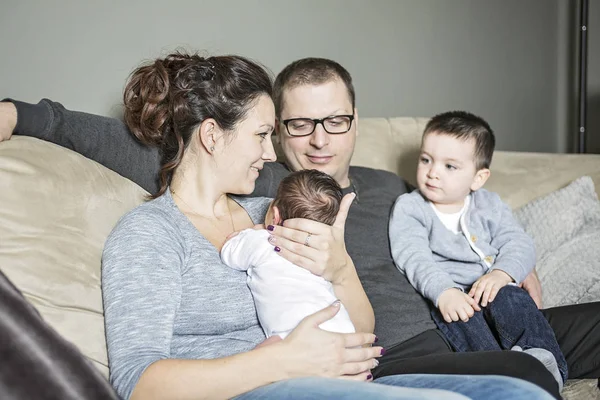 Jovem família feliz com duas crianças em casa — Fotografia de Stock