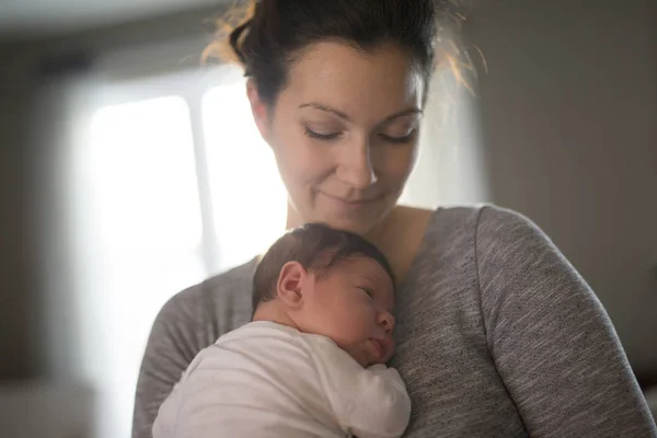 Feliz madre sosteniendo adorable bebé niño en la sala de estar — Foto de Stock