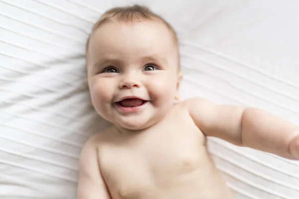 Bonito feliz 7 meses bebê menina na fralda mentindo e jogando — Fotografia de Stock