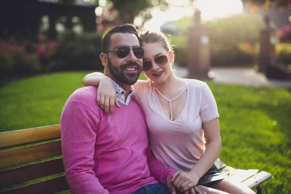 Couple sitting on a bench at the sunset in the city — Stock Photo, Image