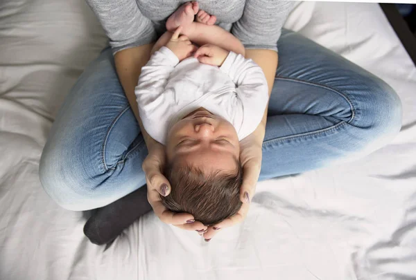 Mãe feliz e bebê deitado na cama em casa — Fotografia de Stock