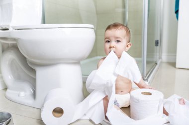 Toddler ripping up toilet paper in bathroom clipart