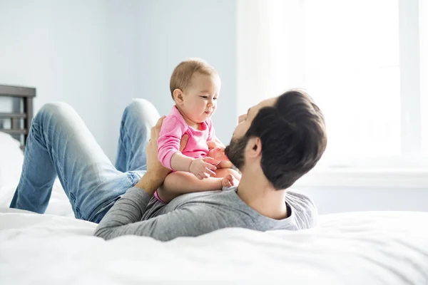 Feliz padre jugando con adorable bebé en el dormitorio — Foto de Stock