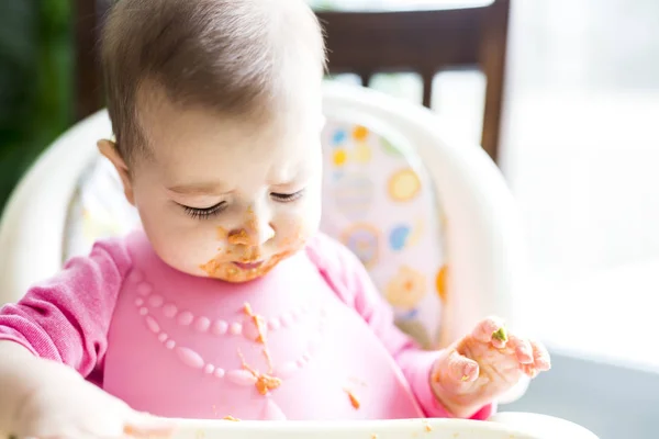 Schattig babymeisje maken van een puinhoop tijdens het voeden zichzelf — Stockfoto