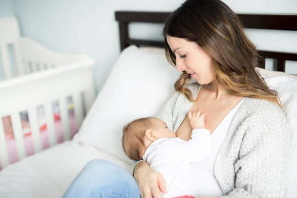 Madre joven sosteniendo a su bebé. Mamá amamantando bebé . — Foto de Stock