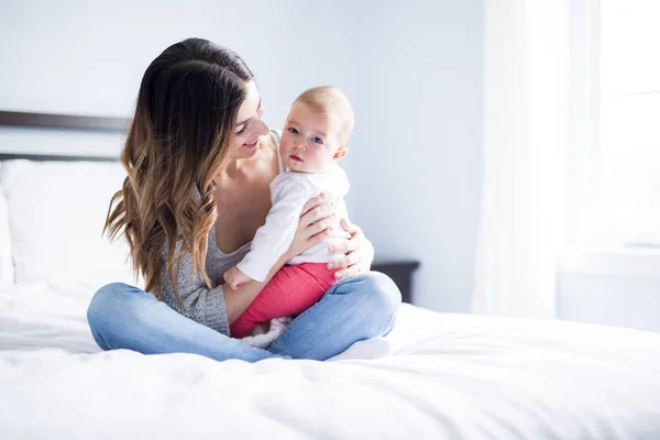 Mère et bébé enfant sur un lit blanc . — Photo