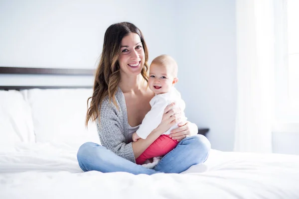 Mother and baby child on a white bed. — Stock Photo, Image