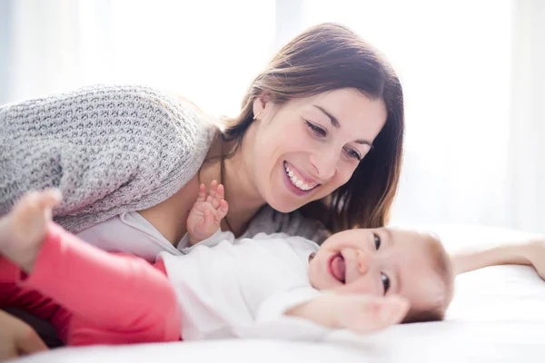 Mère et bébé enfant sur un lit blanc . — Photo