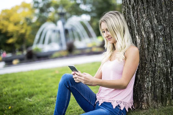 Mulher feliz posando contra uma árvore — Fotografia de Stock