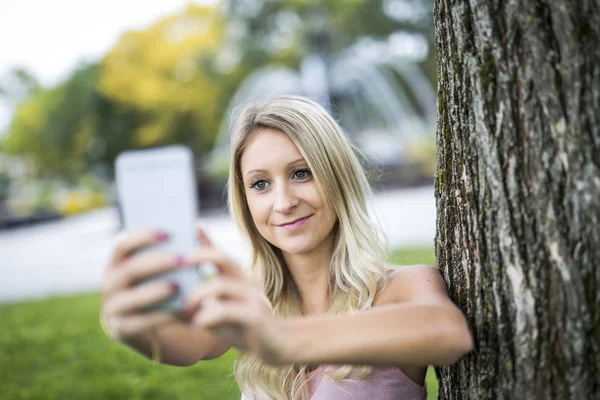 Mulher feliz posando contra uma árvore — Fotografia de Stock