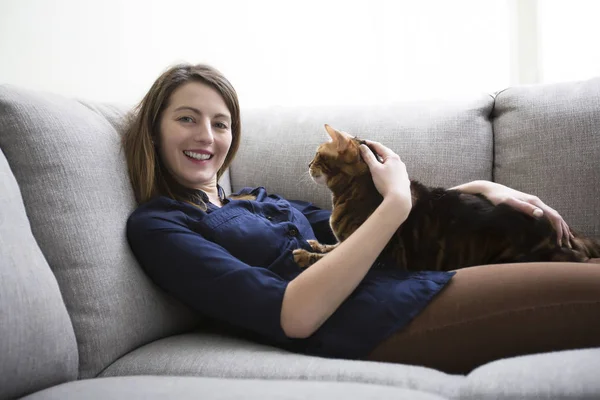 Katze und Frau im Wohnzimmer auf der Couch — Stockfoto