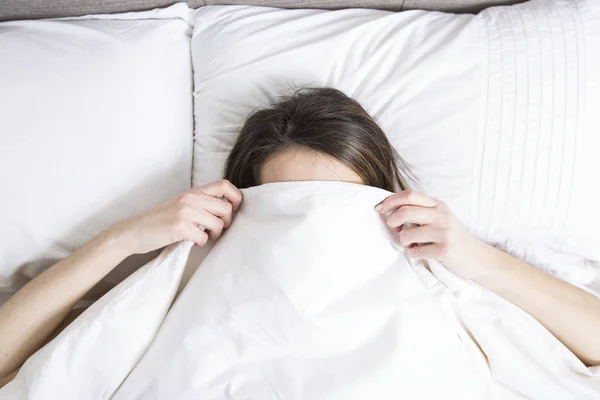 Jovem mulher dormindo no quarto em casa vestindo em branco — Fotografia de Stock