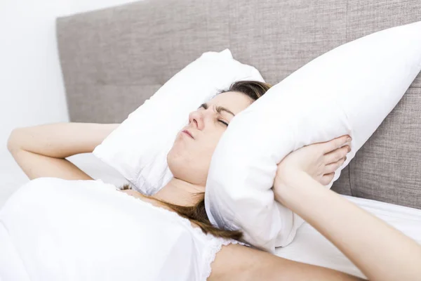 Giovane donna addormentata in camera da letto a casa indossando in bianco — Foto Stock