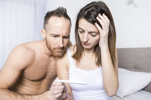 Couple joyeux découvrir les résultats d'un test de grossesse assis sur le lit — Photo