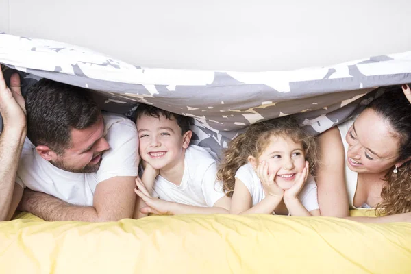 Család, a gyermekek és a haza fogalmát - boldog család, két gyerek otthon takaró alatt — Stock Fotó