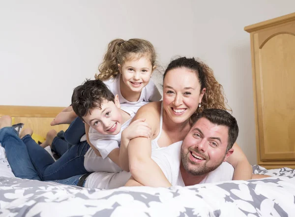 家族、子どもと家庭のコンセプト - 自宅の毛布の下の 2 人の子供と幸せな家庭 — ストック写真