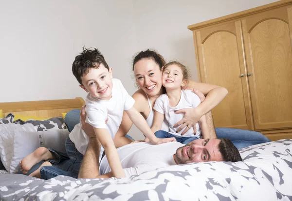 Сім'я, діти та концепція дому - щаслива сім'я з двома дітьми під ковдрою вдома — стокове фото