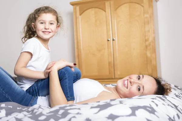 Moeder en dochter thuis in het bed. — Stockfoto