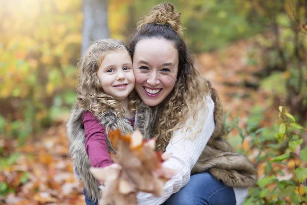 Jonge moeder spelen met haar dochter in de herfst park — Stockfoto