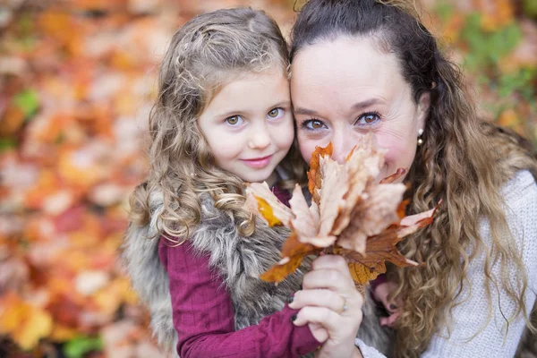 Junge Mutter spielt mit ihrer Tochter im Herbstpark — Stockfoto