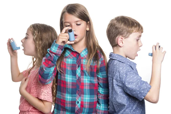 Tres niños usando inhalador para el asma. Fondo blanco — Foto de Stock