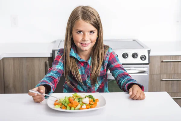 Klein meisje eten groenten geïsoleerd in witte achtergrond — Stockfoto