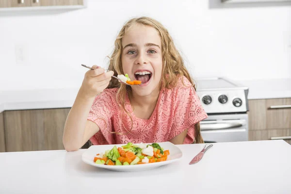 Klein meisje eten groenten geïsoleerd in witte achtergrond — Stockfoto
