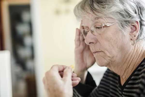 Sjuka äldre kvinna med hennes piller hemma — Stockfoto