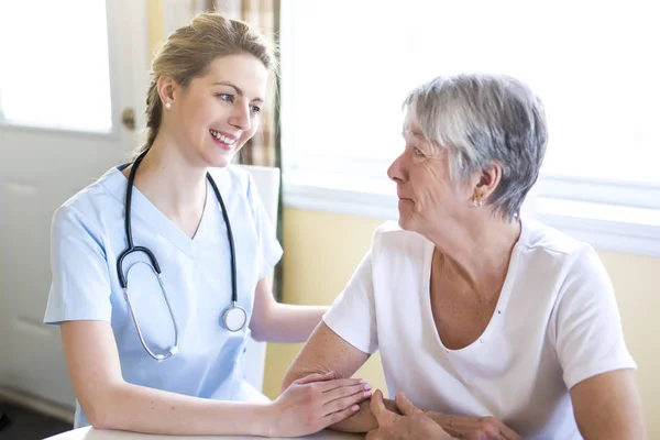 Oudere vrouw met haar verzorger thuis — Stockfoto