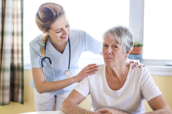 Senior woman with her caregiver at home — Stock Photo, Image
