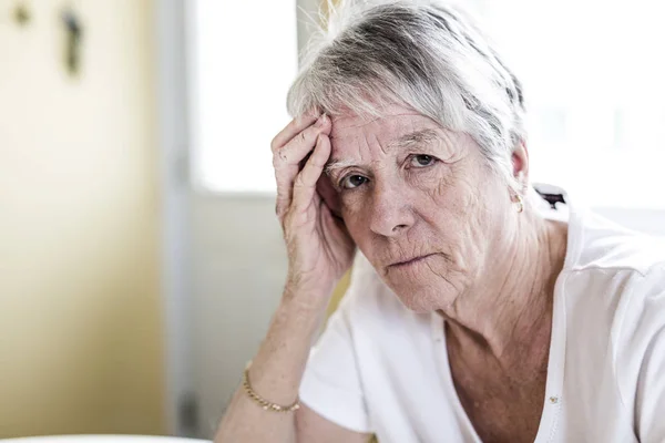 Зрелая женщина дома трогает голову руками, испытывая головную боль. — стоковое фото