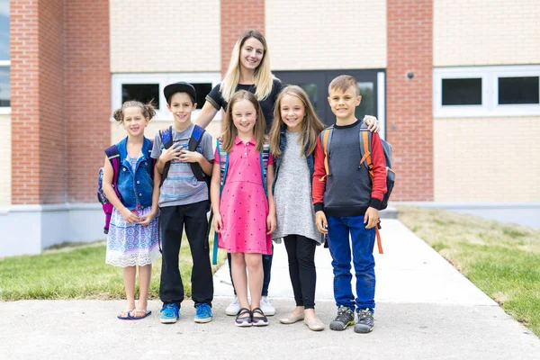 Grand portrait de l'élève de l'école en dehors de la salle de classe portant des sacs avec enseignant — Photo