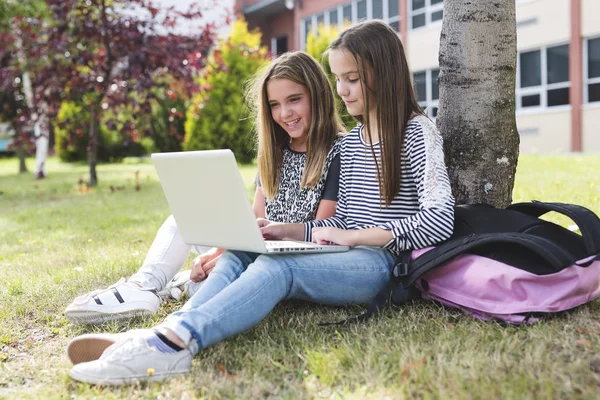 Deux étudiantes souriantes sont assises sur l'herbe . — Photo