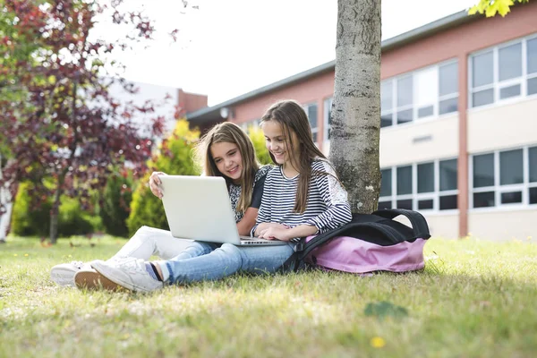Due studentesse sorridenti sono sedute sull'erba . — Foto Stock