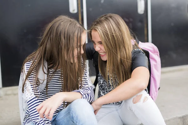 Portrait of two pre teenage girls studying outdoors in school yard — Stock Photo, Image