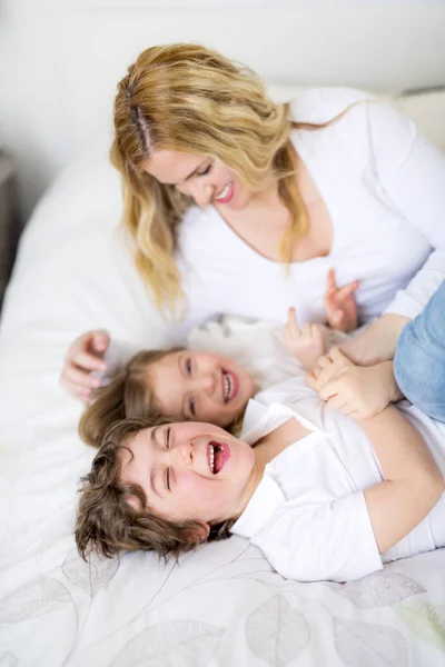 Portrait d'une mère heureuse et de ses enfants couchés sur un lit — Photo